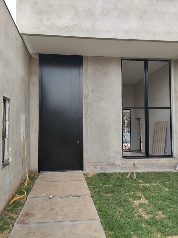 Porta de ACM preta na entrada externa de residência em Brasília-DF