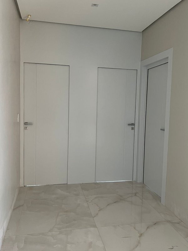 Hall com portas de ACM brancas lisas e piso de mármore, obra da Aluart