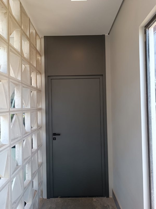 Porta de ACM grafite em corredor com parede de elemento vazado