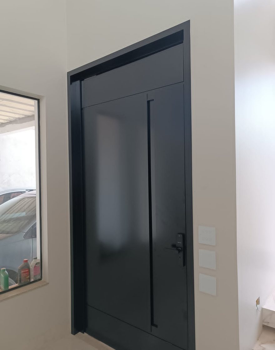Porta pivotante de ACM preta com puxador tubular, fabricada e instalada pela Aluart em Brasília-DF